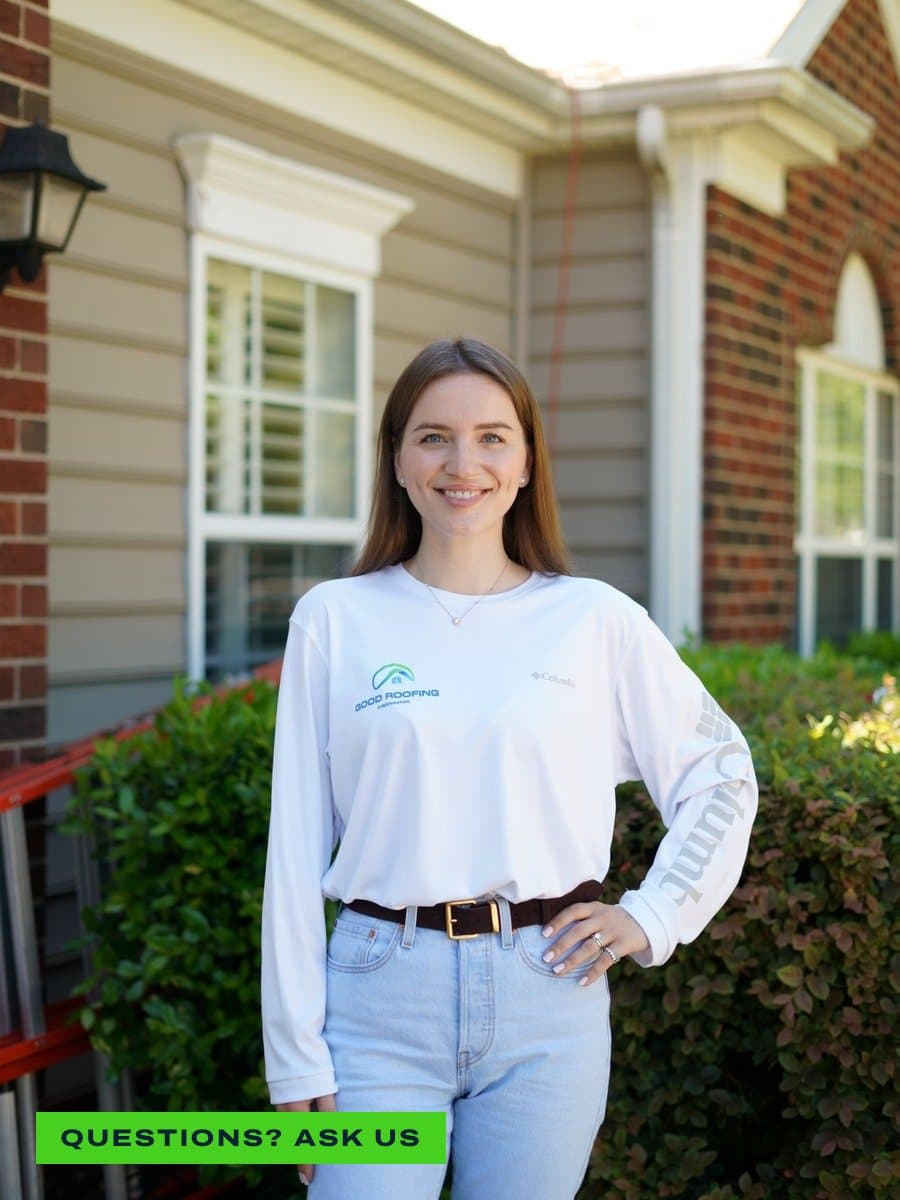 Smiling Good Roofing team member in a branded long-sleeve shirt standing in front of a Charlotte home