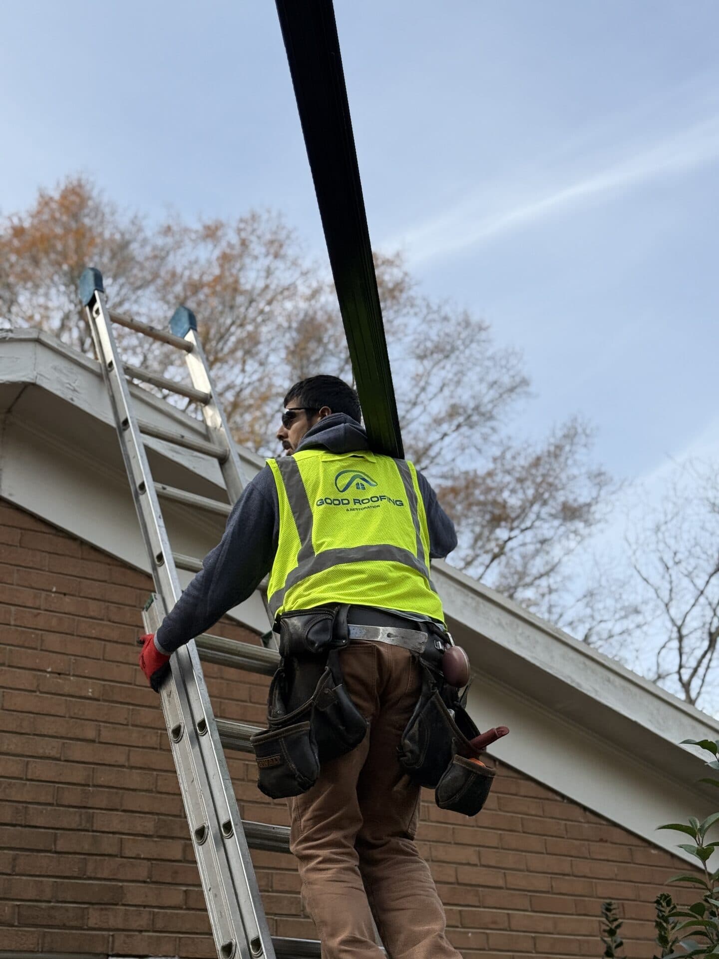 Good Roofing technician carrying roof edge metal up to the eave of a Charlotte home