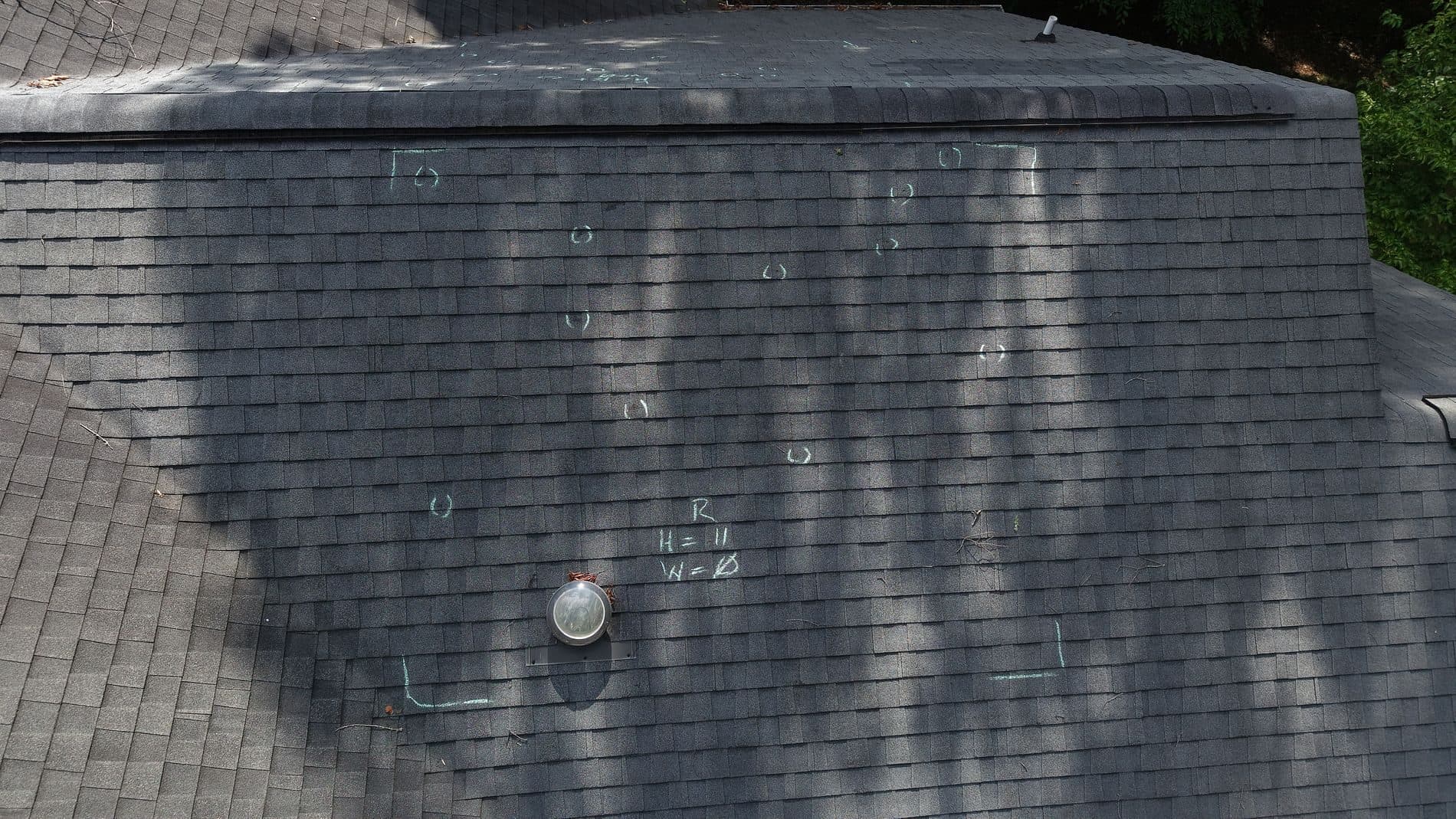 Hail impacts chalk-marked on a shingle roof before the insurance adjuster visit